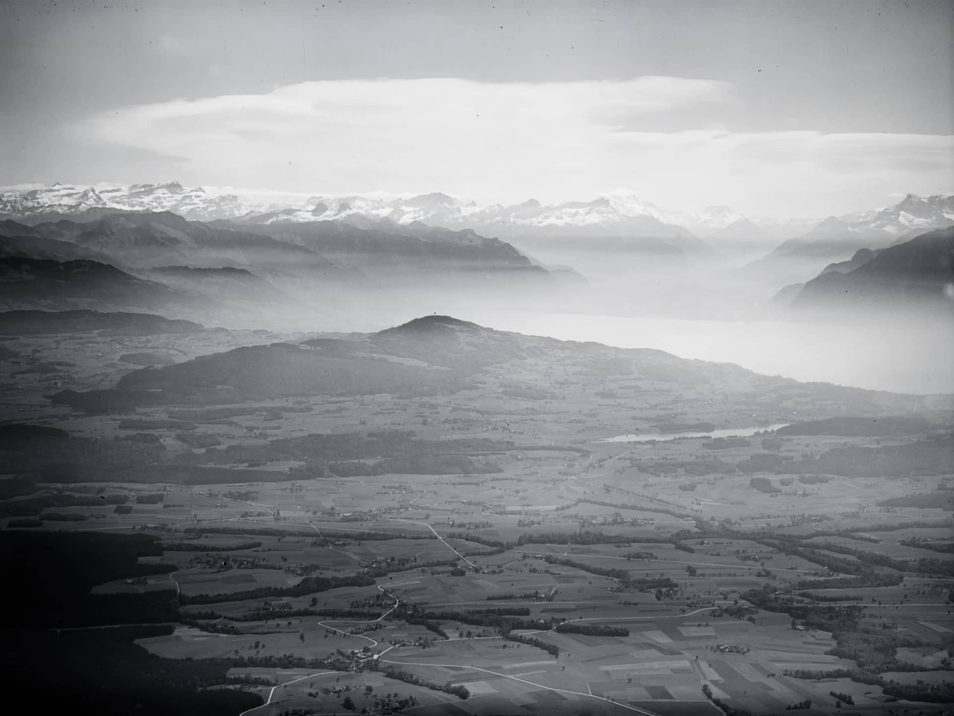 Photographie aérienne de 1934 en noir et blanc : le Lac de Bret, le Mont Pèlerin, le Léman et les Alpes valaisannes
