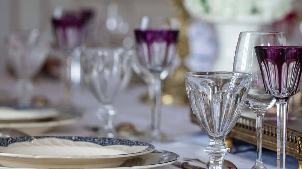 Verres de cristal taillé, violets et clairs, sur une table dressée de la maison de Puidoux