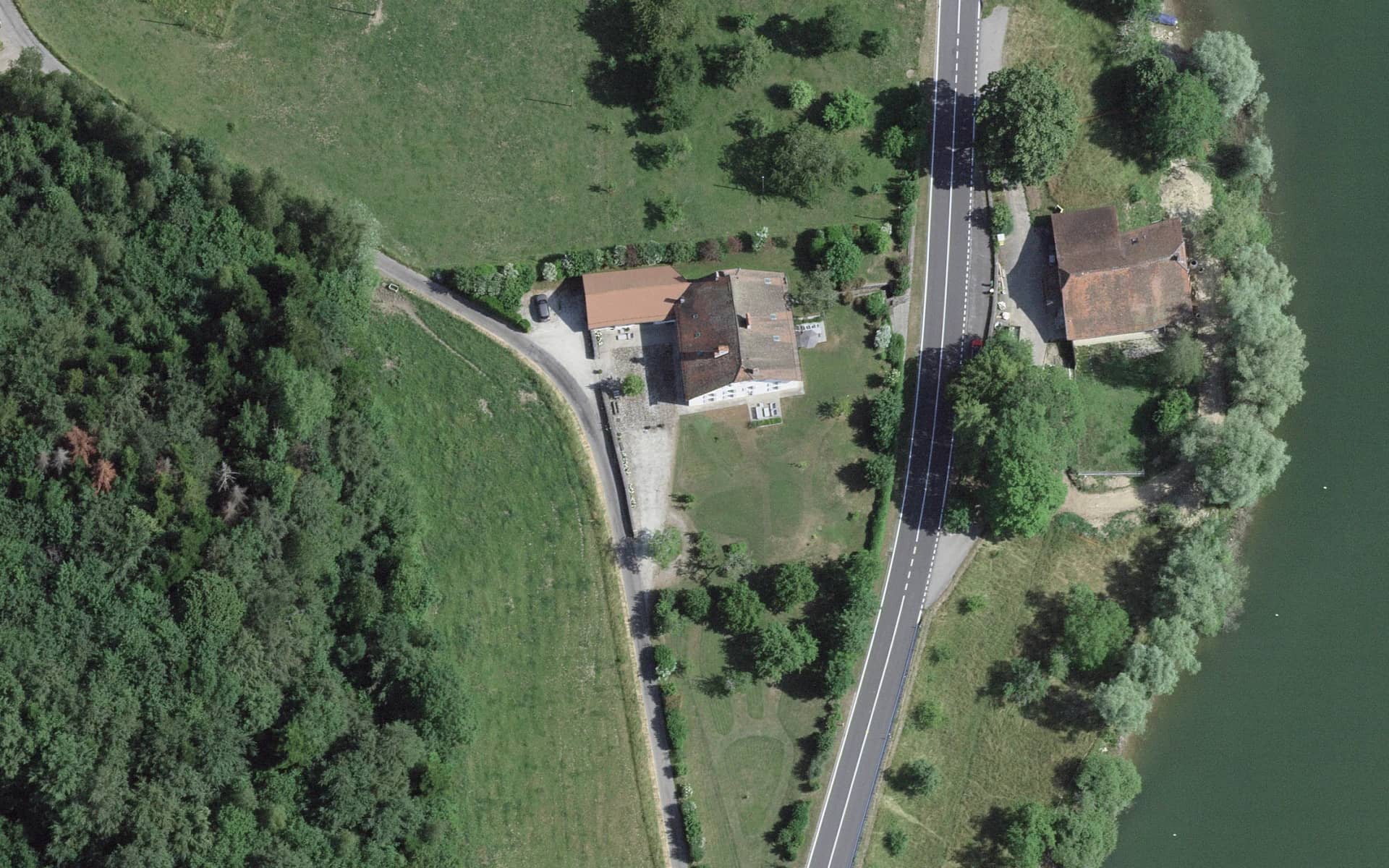 Vue aérienne verticale de la maison de maître, de sa cour et de son jardin, avec la route et la rive du Lac de Bret