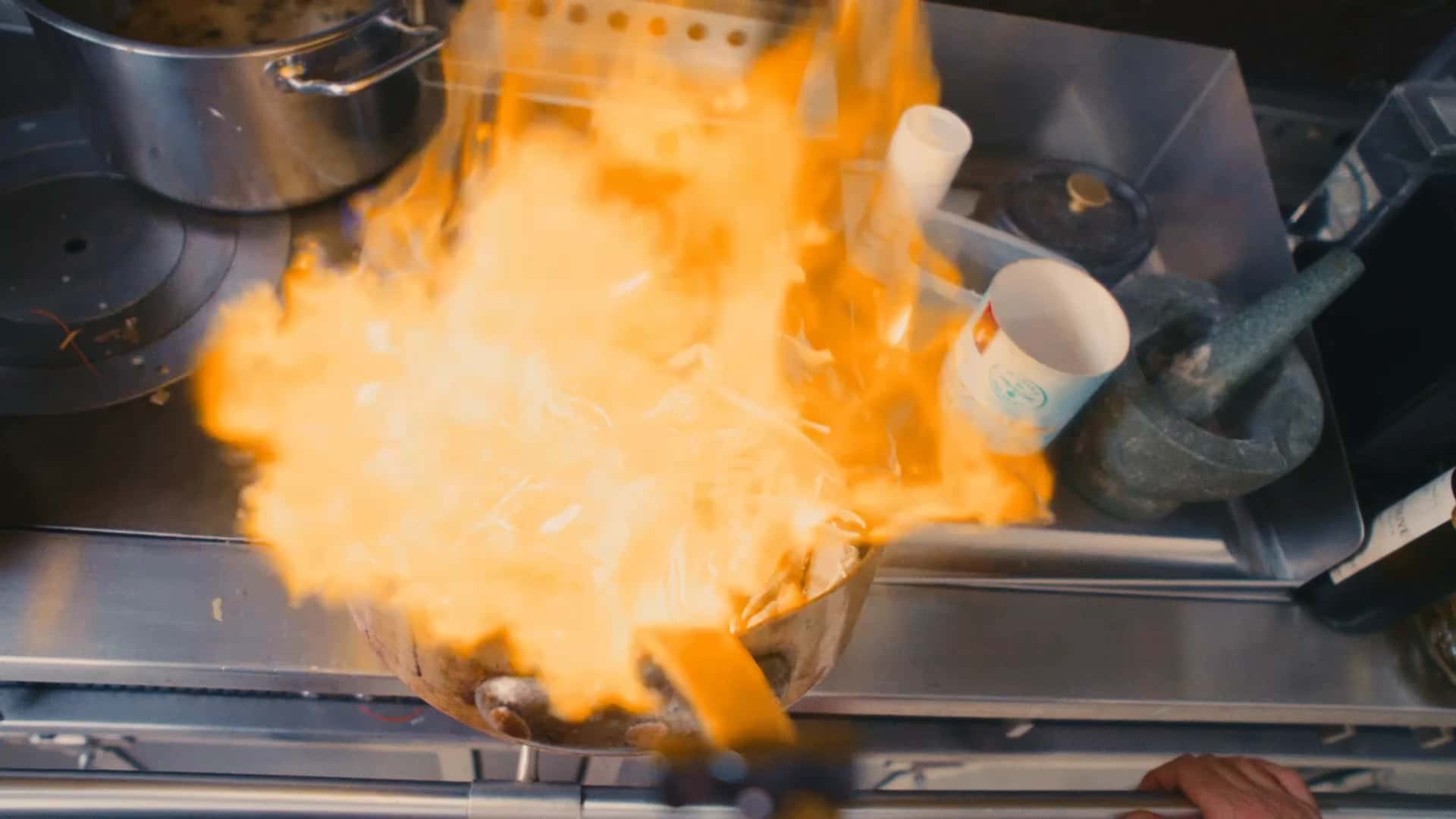 Une gerbe de flammes au-dessus d'une sauteuse en cuivre, sur le fourneau de la cuisine de la maison