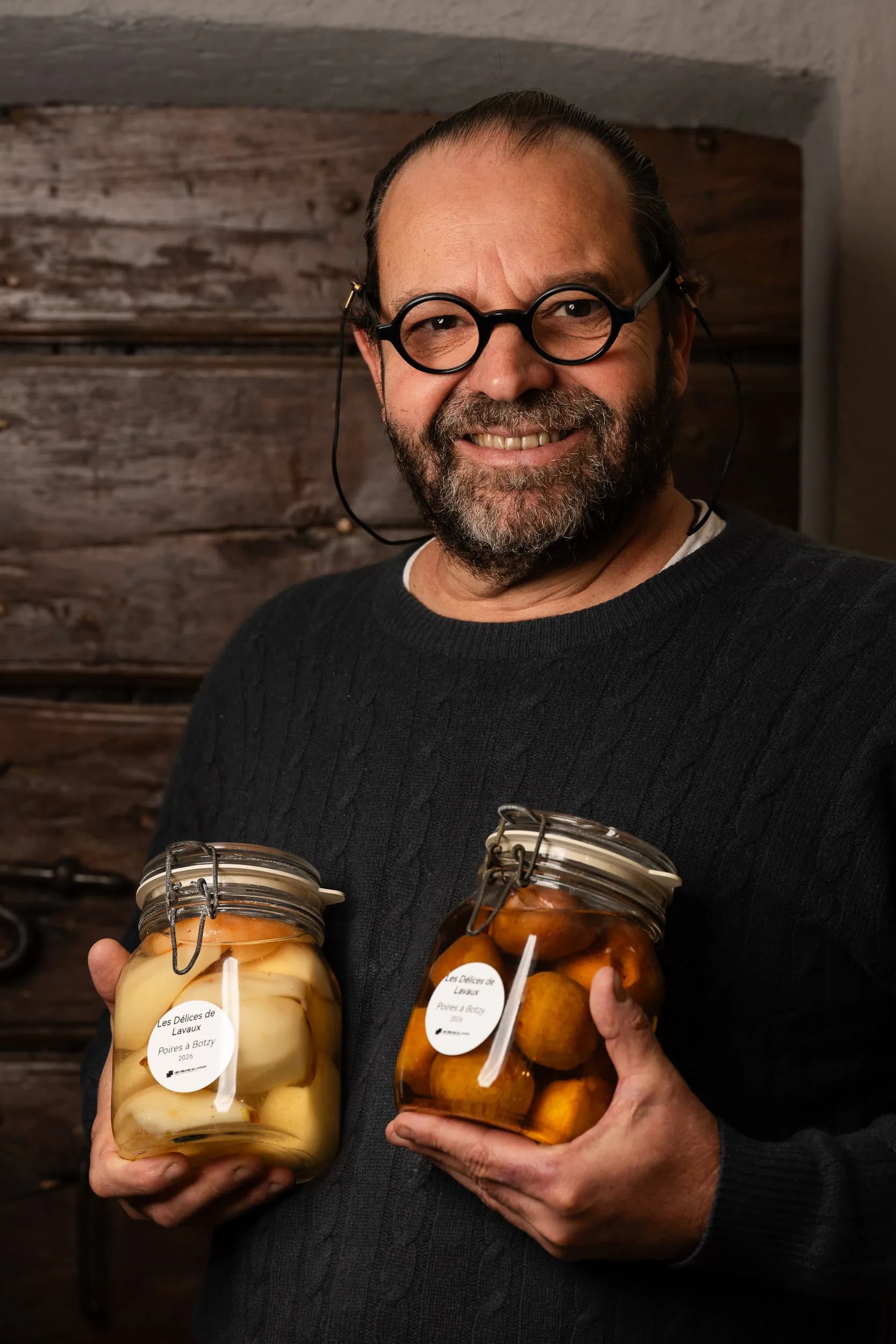Andres Oppenheim, lunettes rondes sur le nez, sourit en tenant deux bocaux de poires au sirop