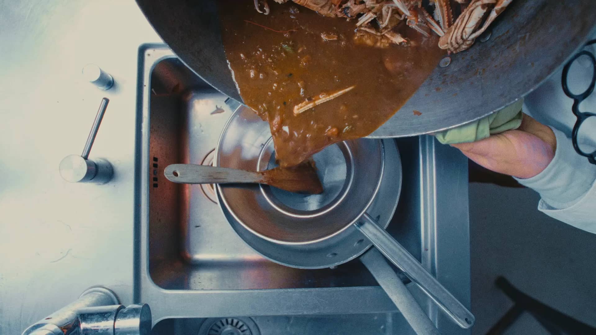 Andres Oppenheim verse une sauce de crustacés à travers un chinois, dans la cuisine de la maison à Puidoux