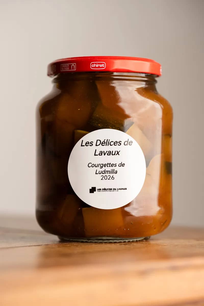 Un bocal de courgettes en morceaux, millésime 2026, à l'étiquette ronde, sur une table en bois