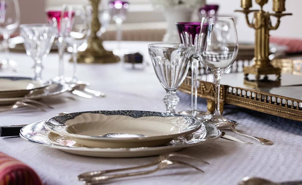 Un couvert de porcelaine ancienne et des verres en cristal, dressés dans la maison
