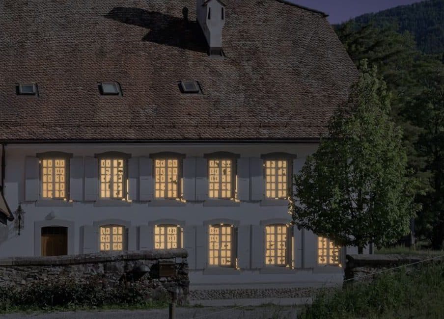 La façade de la maison de maître de Puidoux au soir, toutes ses fenêtres éclairées