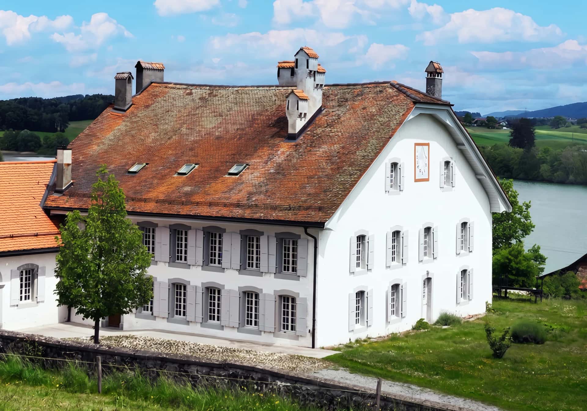 La maison de maître du XVIIIe siècle, son pignon au cadran et sa pelouse, face au Lac de Bret, à Puidoux