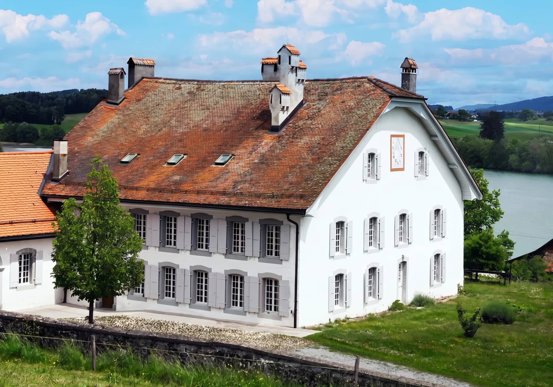 La maison de maître du XVIIIe siècle et sa pelouse, avec le Lac de Bret en arrière-plan, à Puidoux