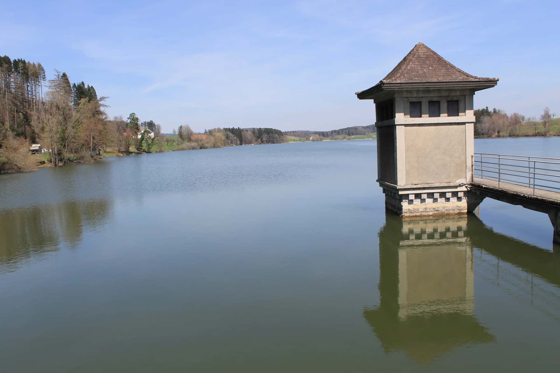La tour de prise d'eau du Lac de Bret, à Puidoux, et son reflet dans le lac calme