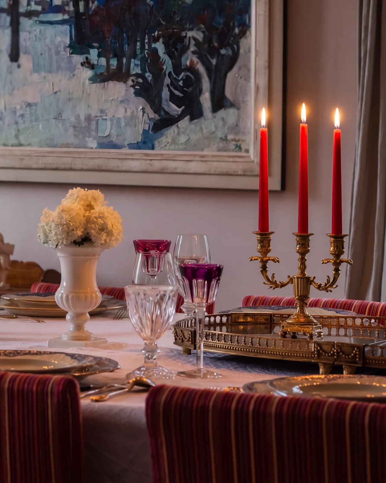 La table de la salle à manger le soir, éclairée par les trois bougies d'un chandelier doré
