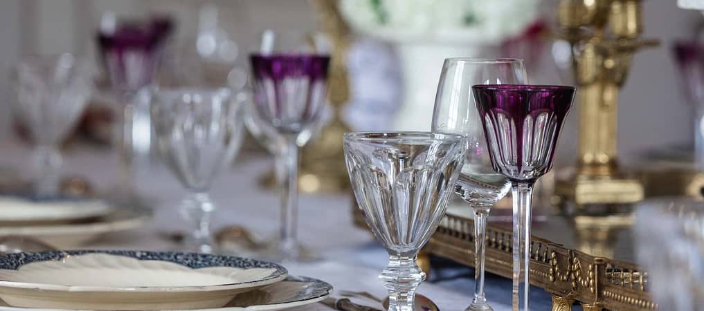 Des verres en cristal et un chandelier doré sur la table dressée de la maison