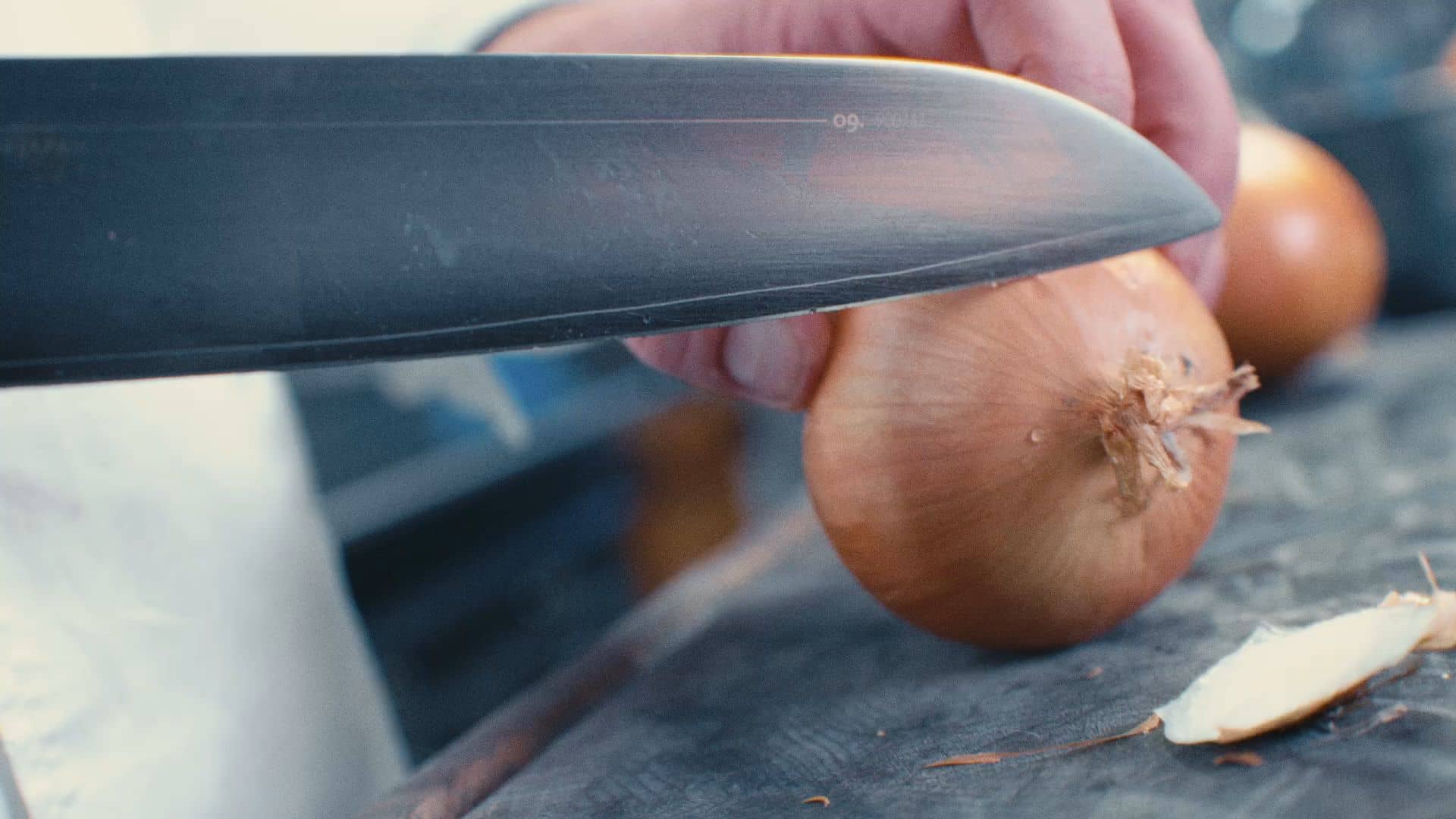 Andres Oppenheim émince un oignon sur la planche, dans la cuisine de la maison, à Puidoux