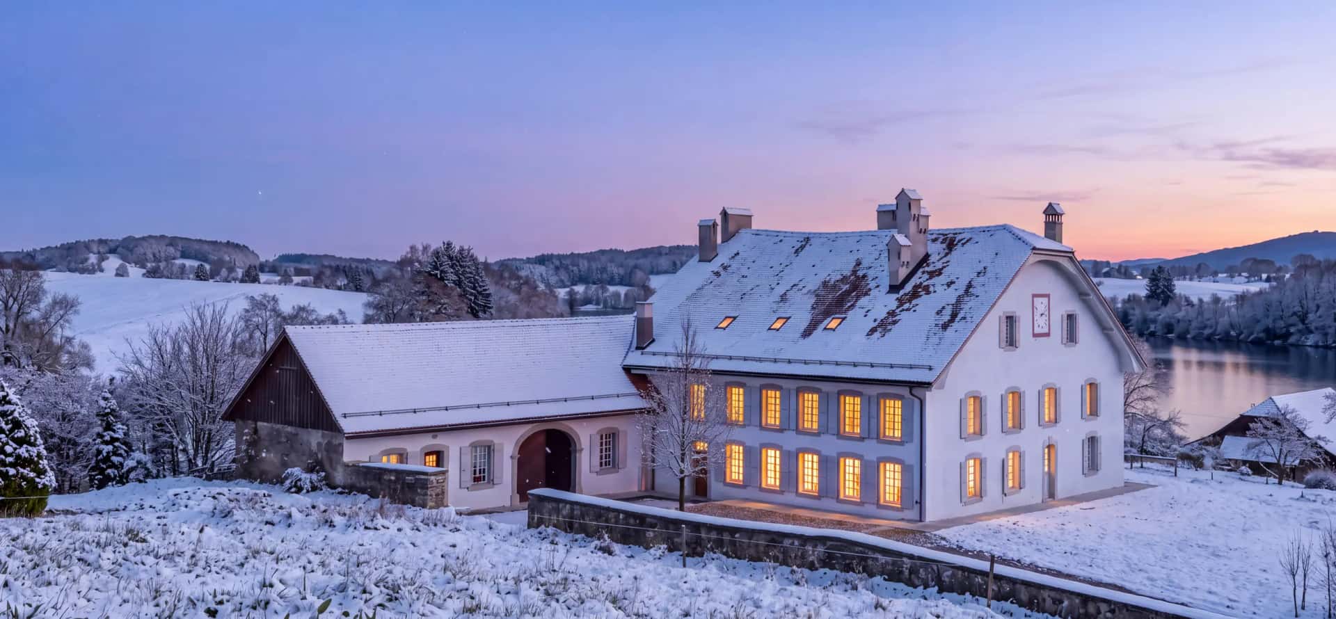 Le même jardin sous la neige, un soir de décembre, la maison éclairée