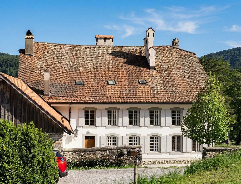 Façade de la maison de maître du XVIIIe siècle à Puidoux, volets gris et toit de tuiles anciennes